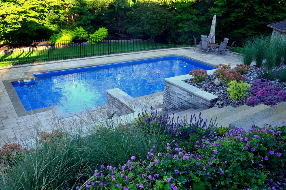 Foto de piscina actual rectangular en patio trasero con adoquines de hormigón
