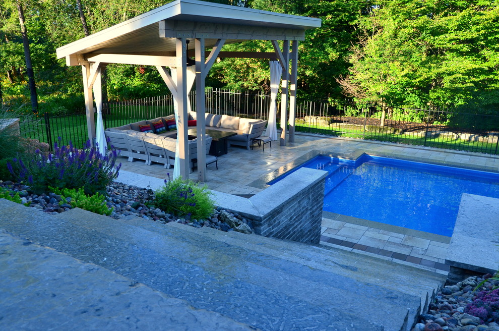 На фото: большой прямоугольный бассейн на заднем дворе в современном стиле с мощением тротуарной плиткой