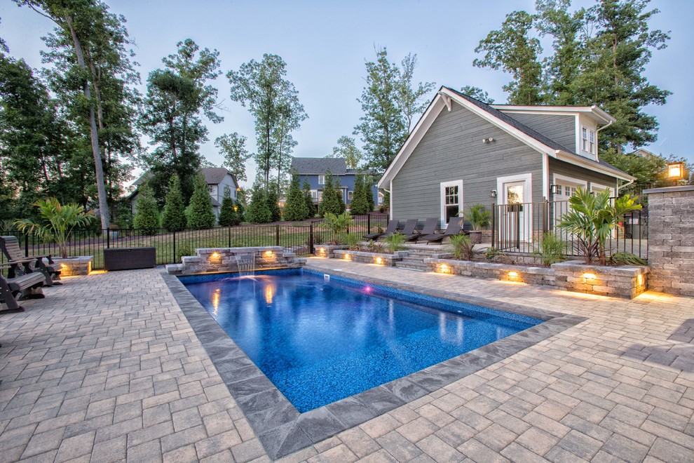 На фото: большой прямоугольный бассейн на заднем дворе в стиле модернизм с домиком у бассейна и мощением тротуарной плиткой с