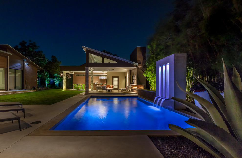 Immagine di una grande piscina minimal rettangolare dietro casa con una dépendance a bordo piscina e pavimentazioni in cemento