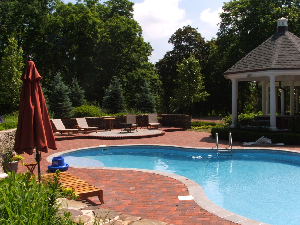 Classic custom shaped swimming pool in Chicago with brick paving.