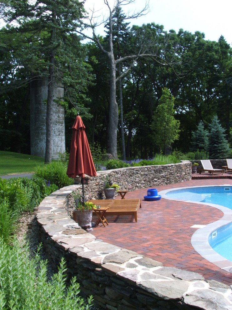 Design ideas for a traditional custom shaped swimming pool in Chicago with brick paving.