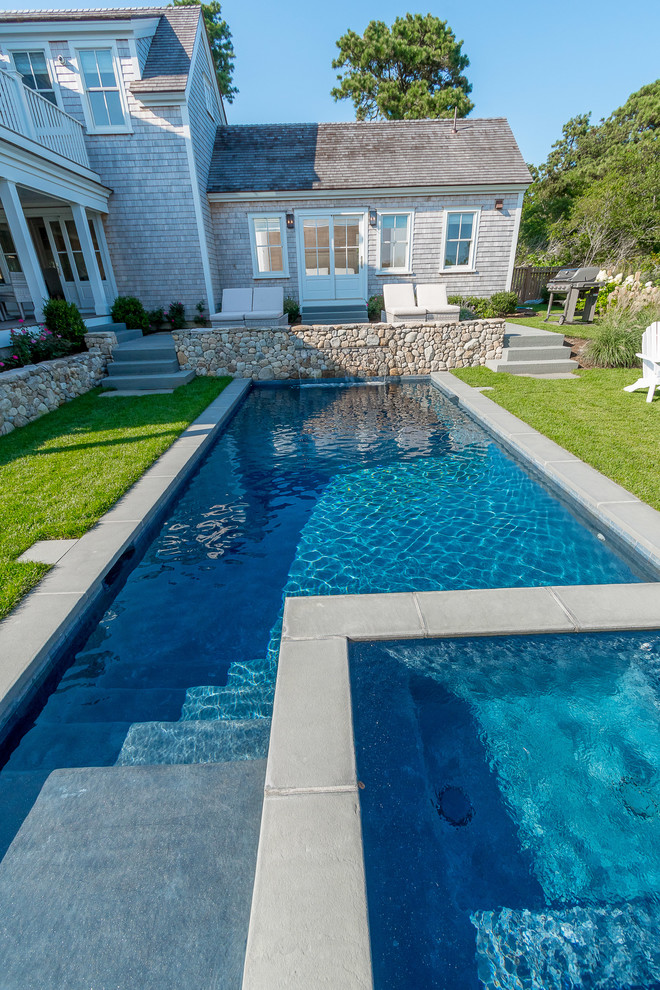Großer Maritimer Schwimmteich hinter dem Haus in rechteckiger Form mit Wasserspiel und Natursteinplatten in Boston