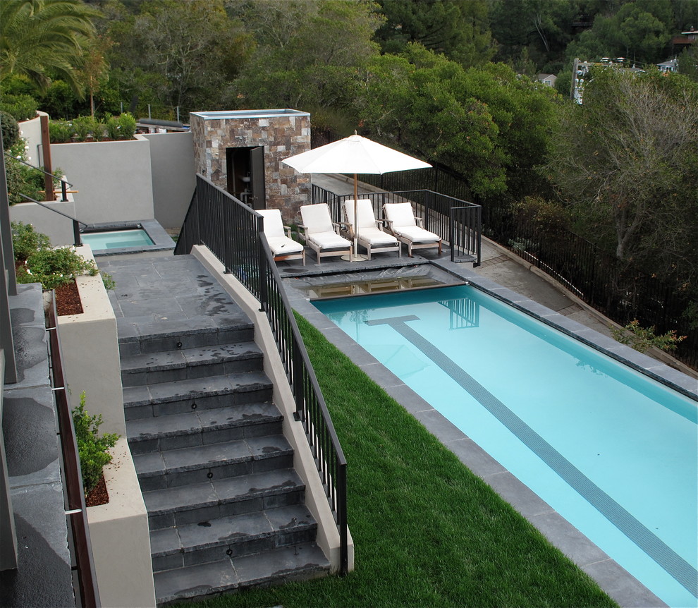 Diseño de piscina actual rectangular en patio trasero con adoquines de piedra natural