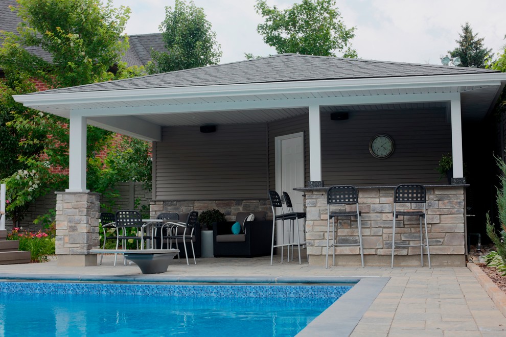 Diseño de casa de la piscina y piscina tradicional grande en patio trasero con adoquines de hormigón