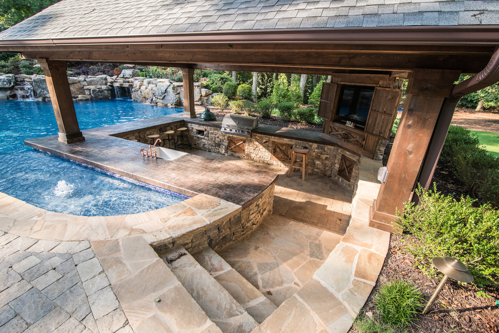 Esempio di una piscina naturale tropicale personalizzata dietro casa con pavimentazioni in cemento e una dépendance a bordo piscina