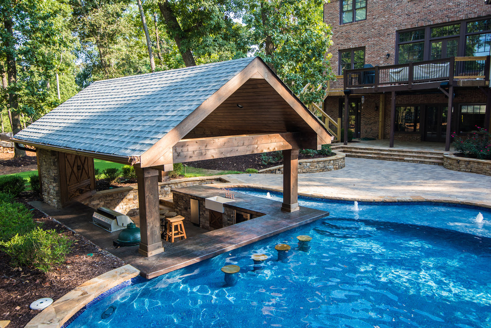 На фото: естественный бассейн произвольной формы на заднем дворе в морском стиле с мощением тротуарной плиткой и домиком у бассейна с