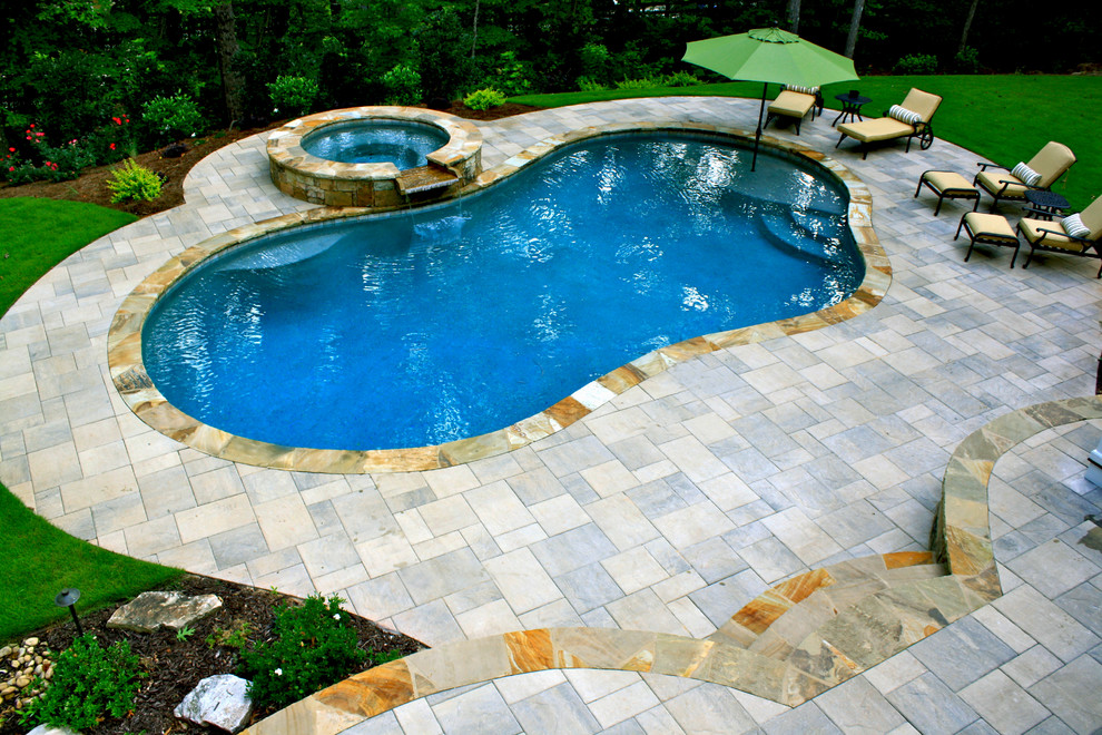Diseño de piscinas y jacuzzis alargados tradicionales de tamaño medio tipo riñón en patio trasero con adoquines de hormigón