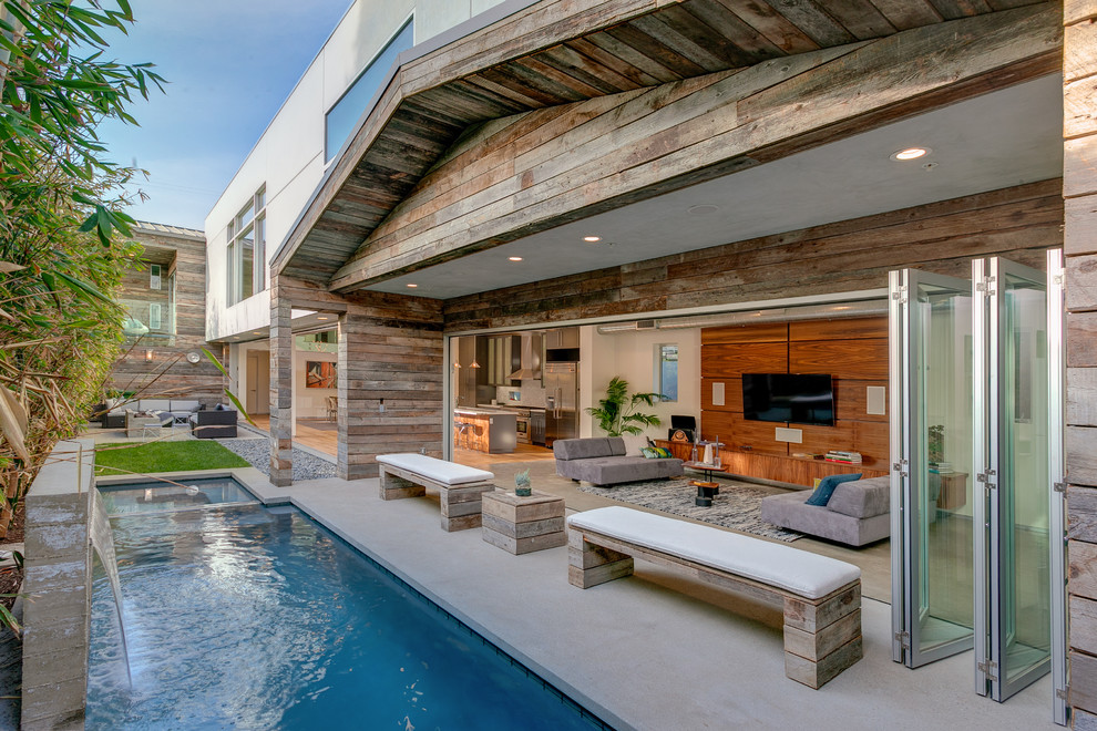 Medium sized contemporary back rectangular swimming pool in Los Angeles with a water feature and concrete slabs.