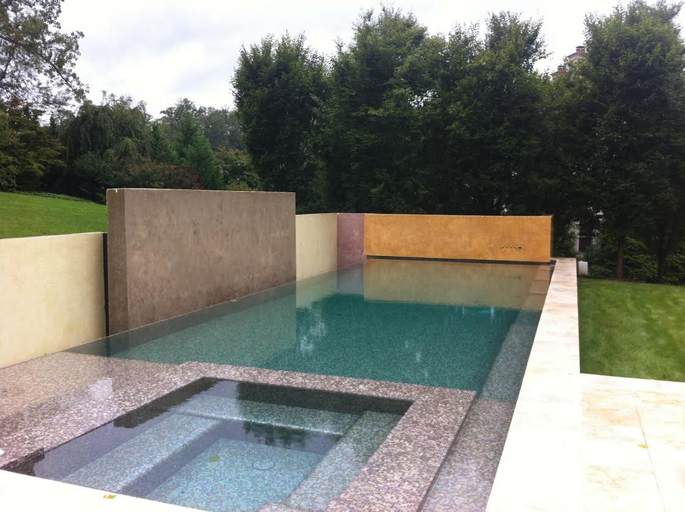 Idee per una grande piscina fuori terra design rettangolare dietro casa con una vasca idromassaggio e lastre di cemento