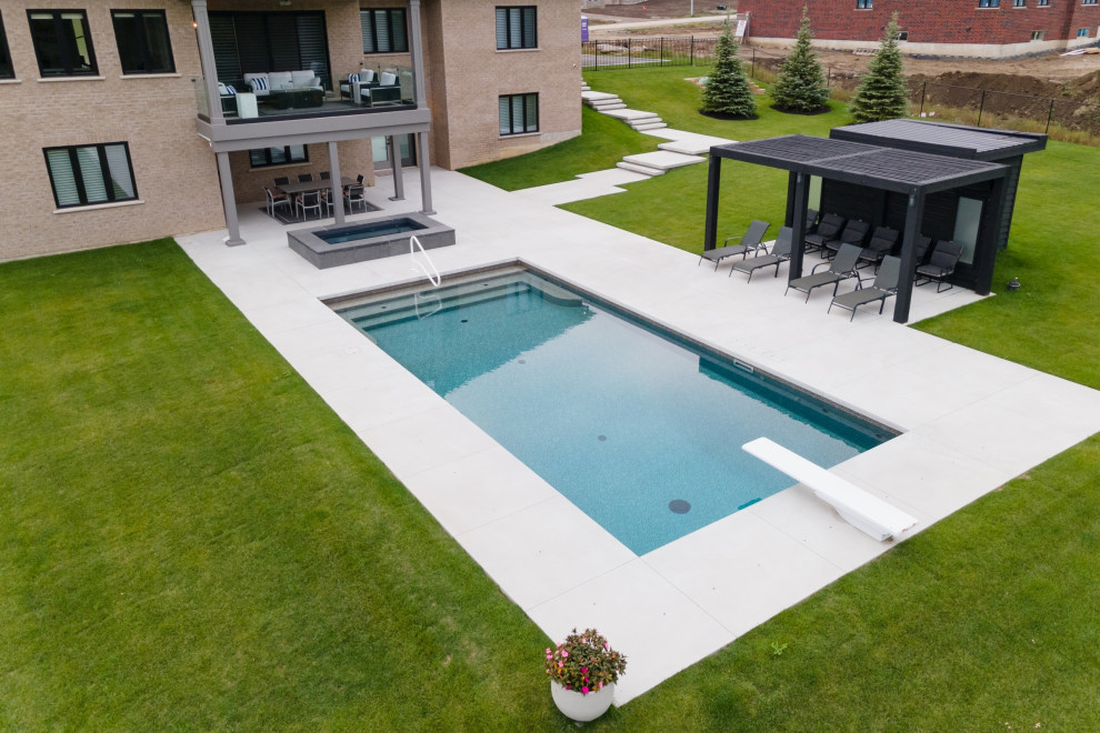 Свежая идея для дизайна: прямоугольный бассейн среднего размера на заднем дворе в современном стиле с покрытием из бетонных плит и домиком у бассейна - отличное фото интерьера