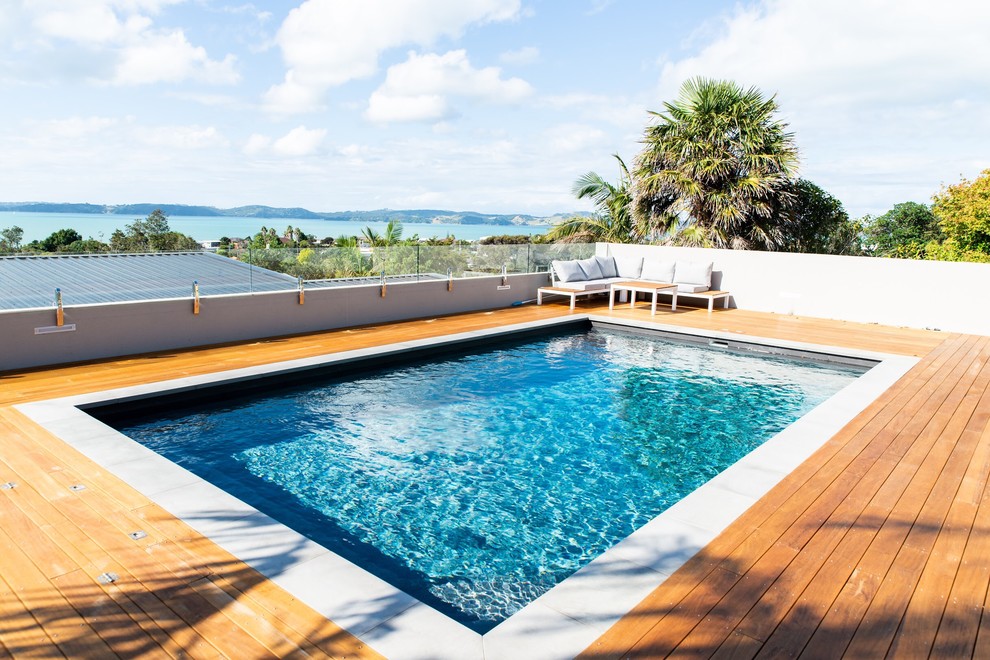 Exemple d'une grande piscine hors-sol et arrière bord de mer rectangle avec une terrasse en bois.