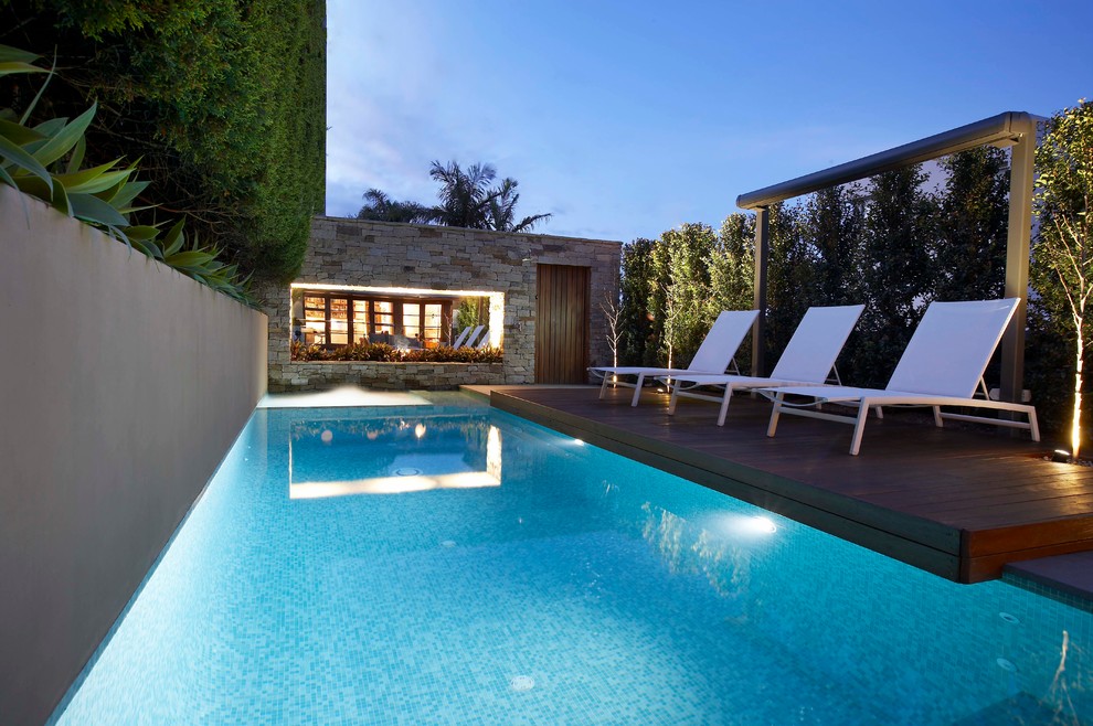 Inspiration pour une piscine design de taille moyenne et rectangle avec une terrasse en bois.