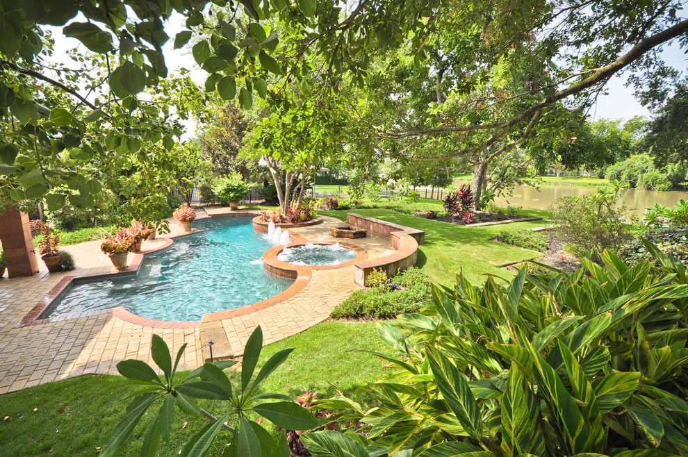 Example of a mid-sized classic backyard stone and round hot tub design in Houston