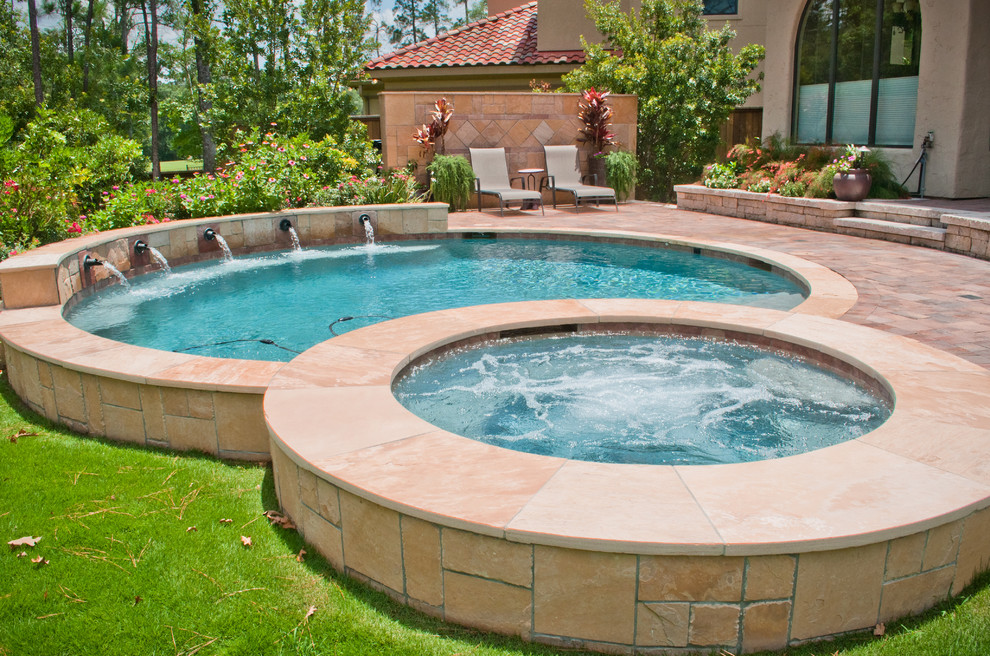 Cette photo montre une petite piscine arrière chic ronde avec un bain bouillonnant et des pavés en pierre naturelle.