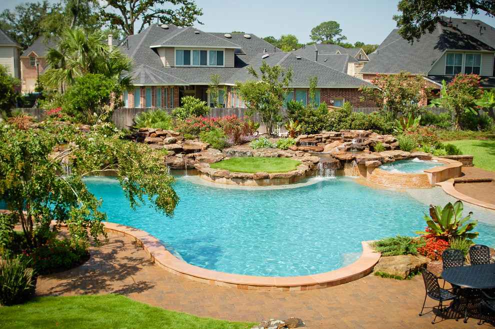 Immagine di una piscina tradizionale personalizzata di medie dimensioni e dietro casa con fontane e pavimentazioni in mattoni