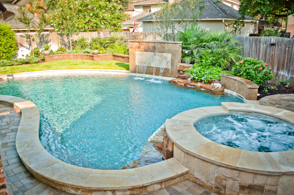 Großer Klassischer Whirlpool hinter dem Haus in Nierenform mit Natursteinplatten in Houston
