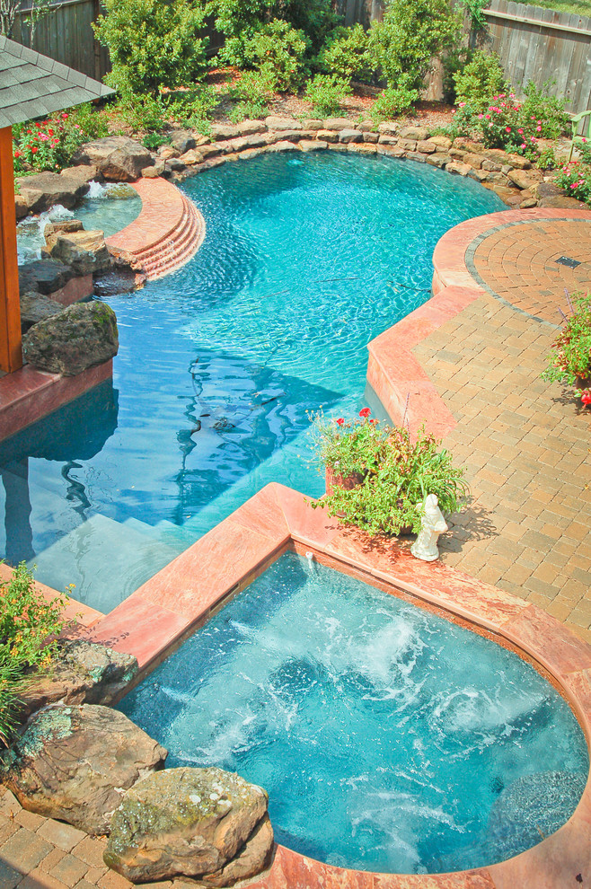Photo of a medium sized classic back custom shaped swimming pool in Houston with a water feature and natural stone paving.