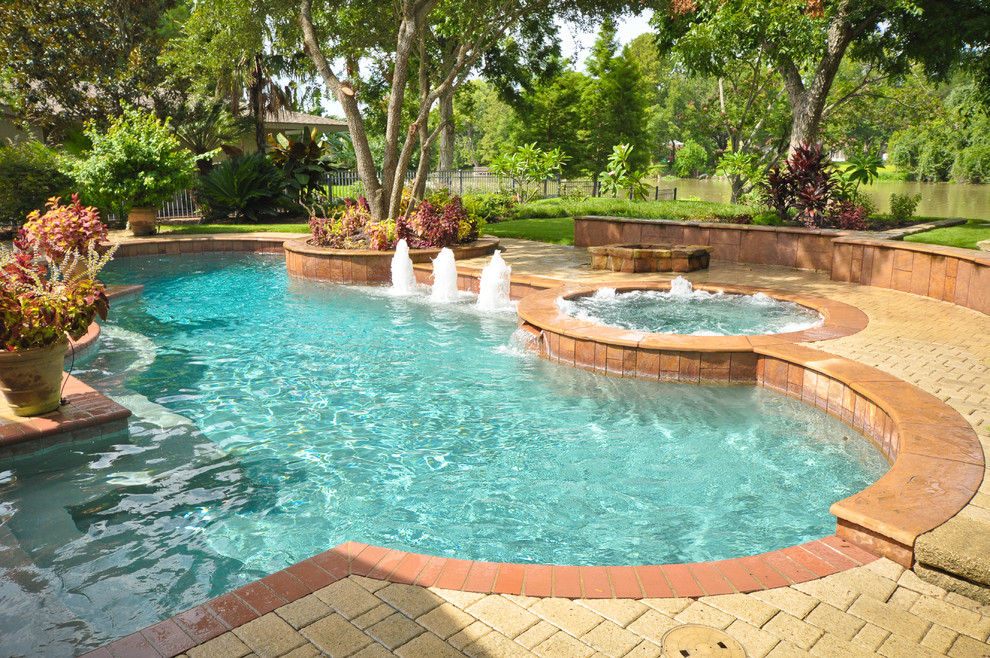 Imagen de piscinas y jacuzzis tradicionales de tamaño medio redondeados en patio trasero con adoquines de piedra natural