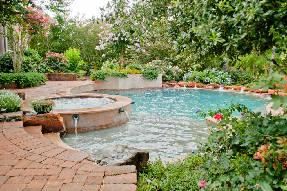 Diseño de piscina clásica grande redondeada en patio trasero con adoquines de ladrillo