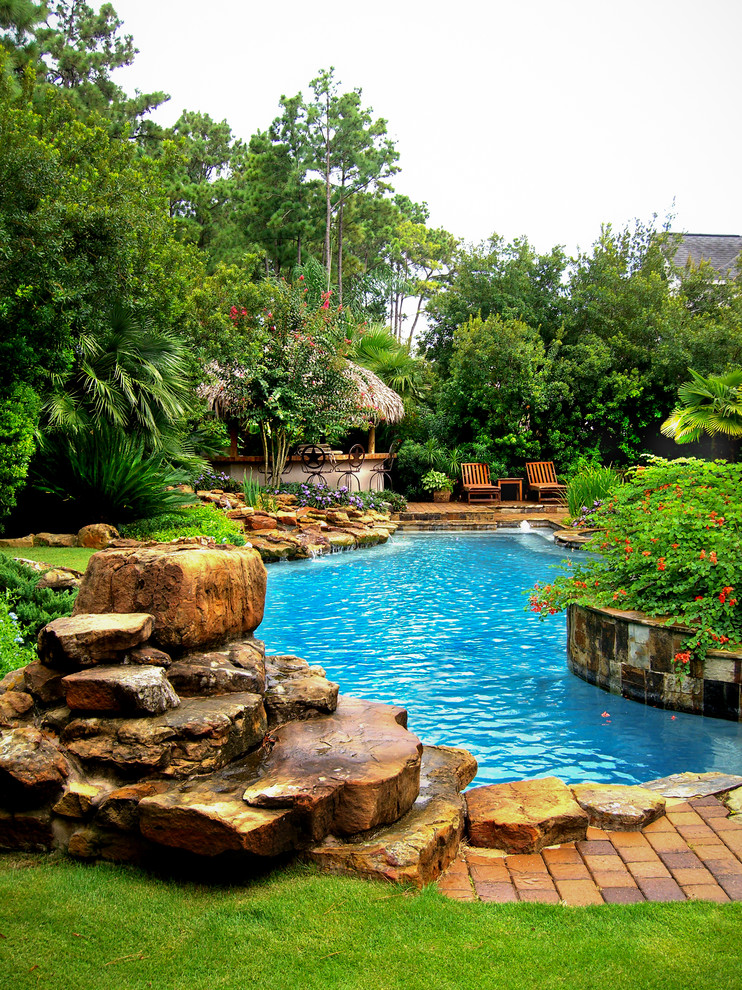 Modelo de piscina clásica grande redondeada en patio trasero con adoquines de ladrillo