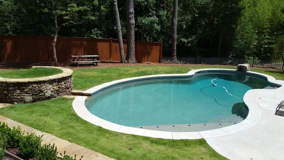 Inspiration pour une piscine arrière et naturelle traditionnelle sur mesure et de taille moyenne avec une dalle de béton et un point d'eau.