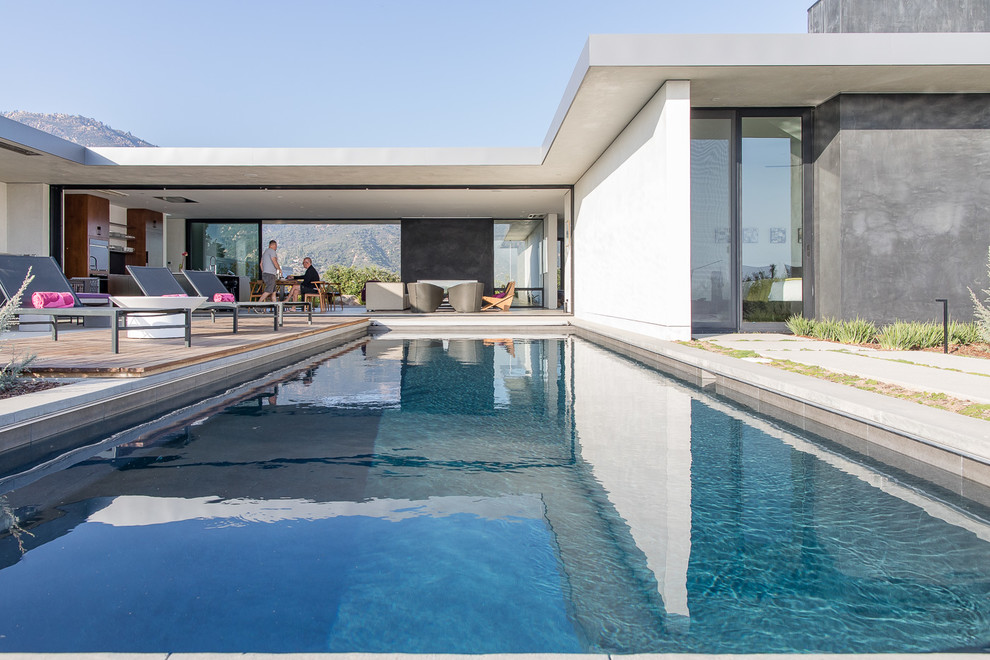 Idées déco pour une piscine arrière contemporaine de taille moyenne et rectangle avec une terrasse en bois.