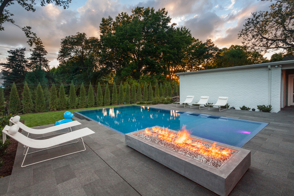 Medium sized contemporary back rectangular swimming pool in Kansas City with natural stone paving.