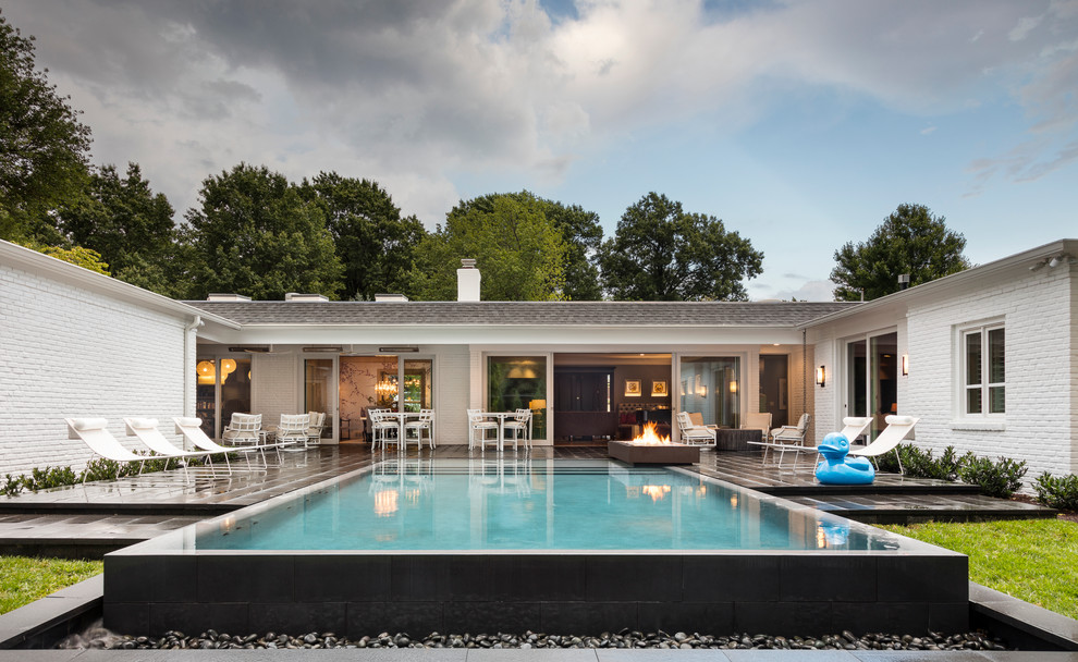 Foto di una piscina a sfioro infinito chic rettangolare di medie dimensioni e dietro casa con pavimentazioni in pietra naturale
