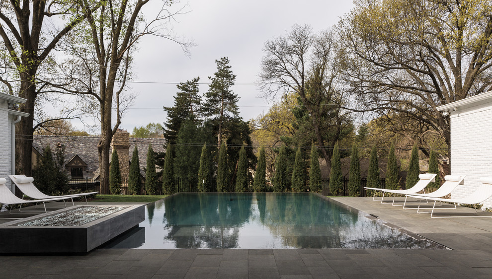 Стильный дизайн: прямоугольный бассейн-инфинити среднего размера на заднем дворе в стиле неоклассика (современная классика) с покрытием из каменной брусчатки - последний тренд