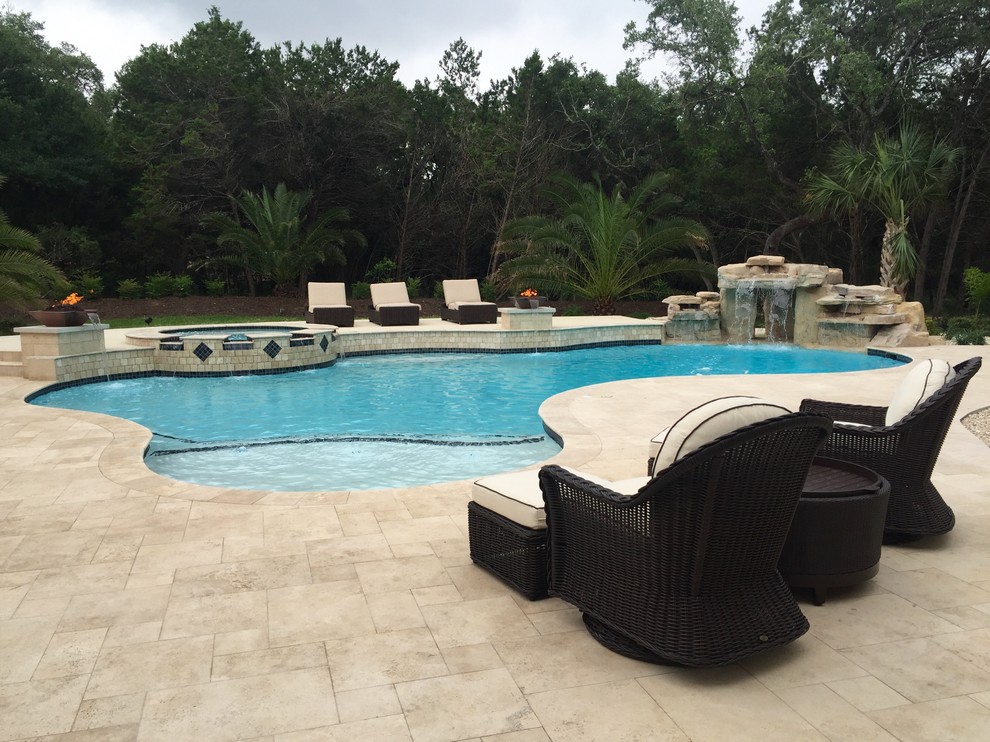 Diseño de piscina con fuente natural actual grande tipo riñón en patio trasero con adoquines de piedra natural