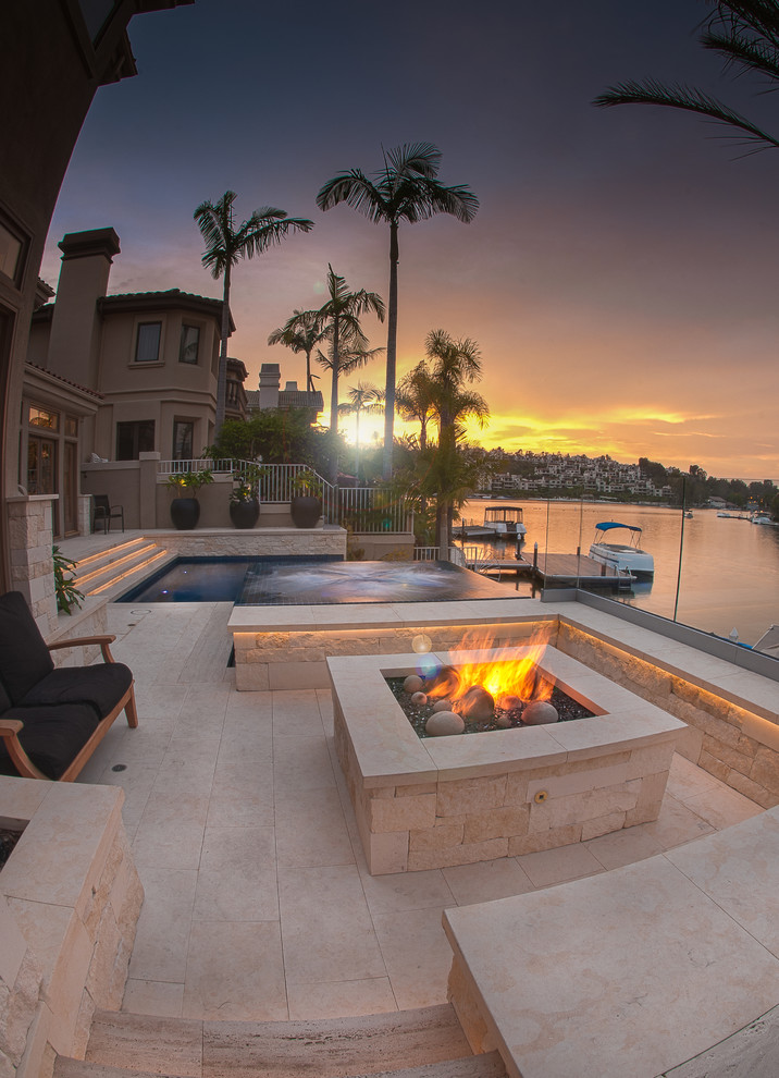 Photo of a medium sized modern back patio in Orange County with natural stone paving, a fire feature and no cover.