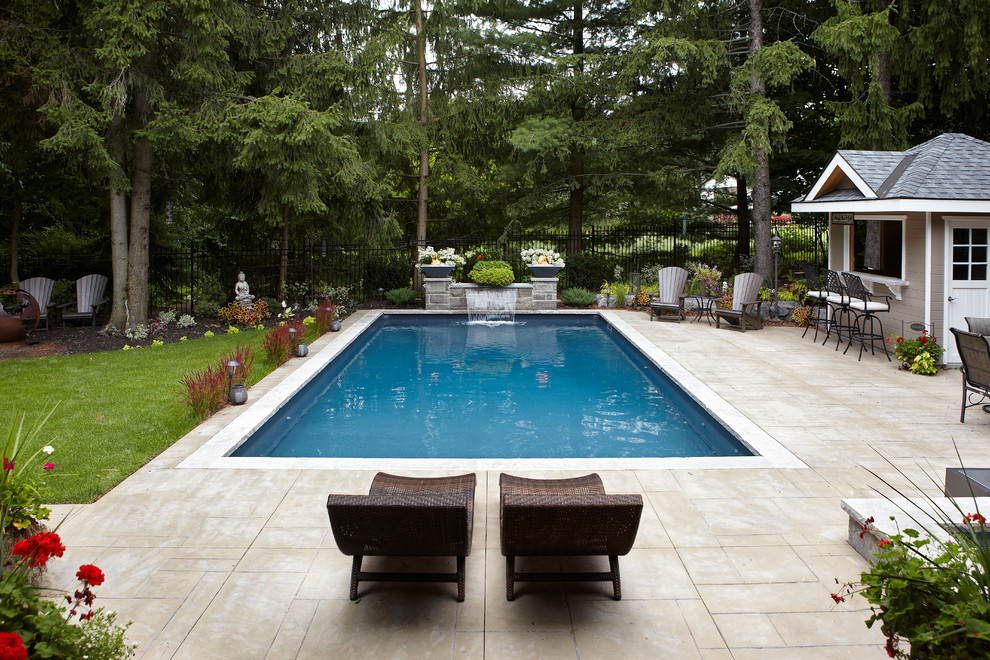 Foto di una piscina monocorsia design rettangolare di medie dimensioni e dietro casa con fontane e pavimentazioni in cemento