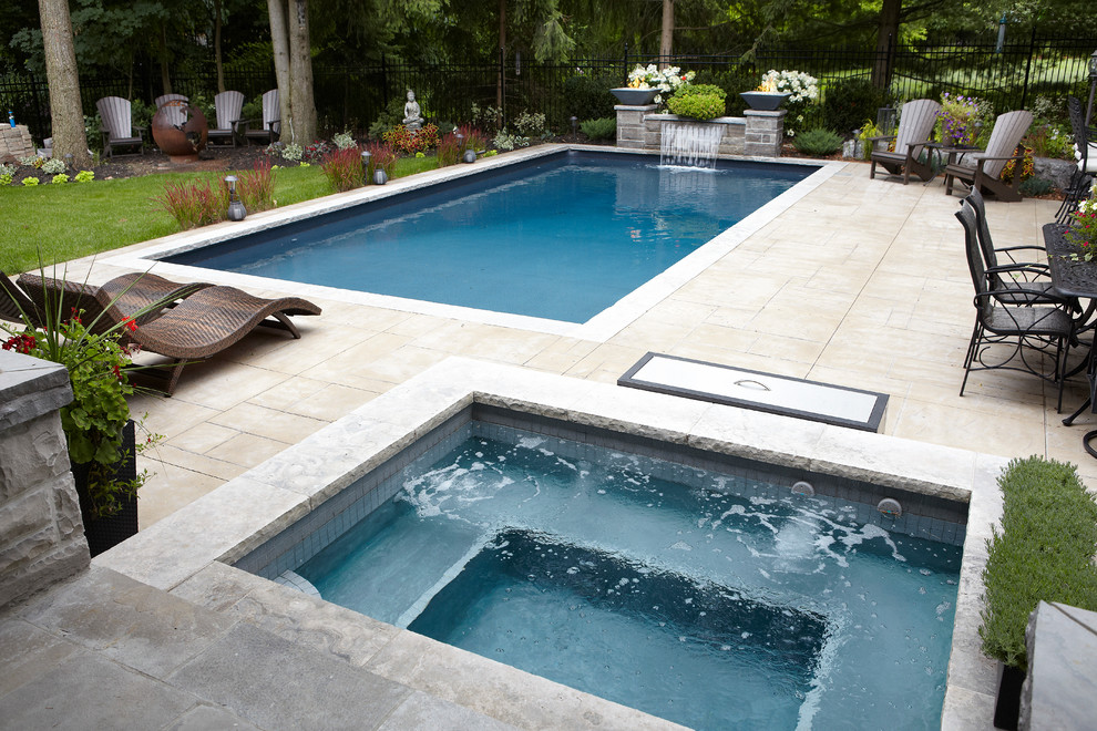 Imagen de piscina con fuente alargada actual de tamaño medio rectangular en patio trasero con adoquines de hormigón
