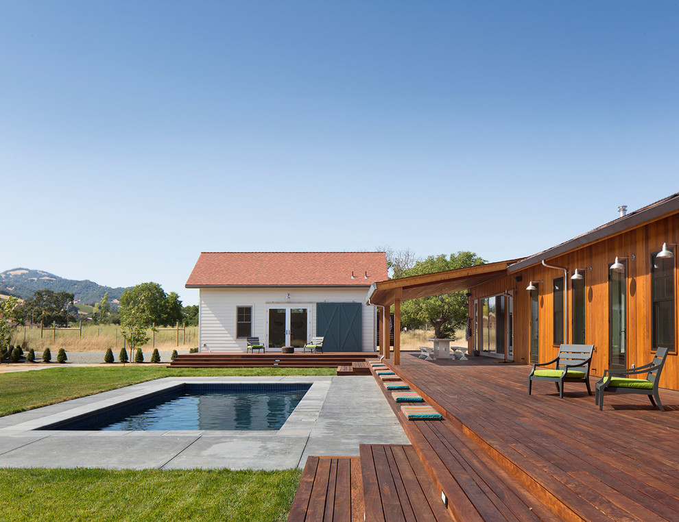Inspiration för mellanstora lantliga rektangulär pooler på baksidan av huset, med poolhus och trädäck