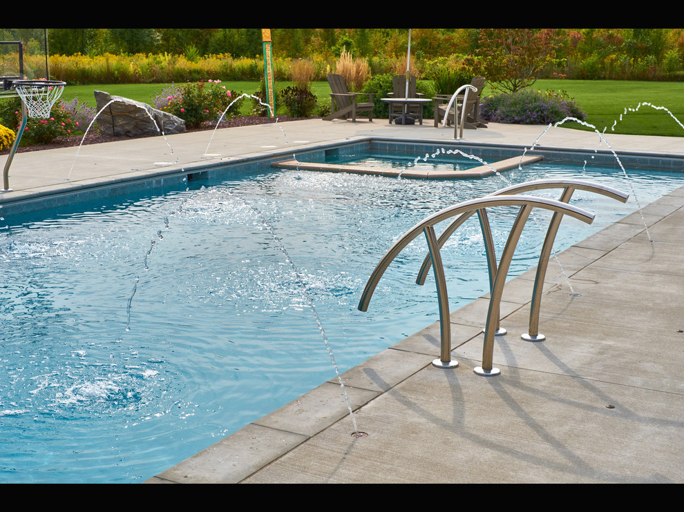 Esempio di una piscina country rettangolare di medie dimensioni e dietro casa con lastre di cemento e fontane