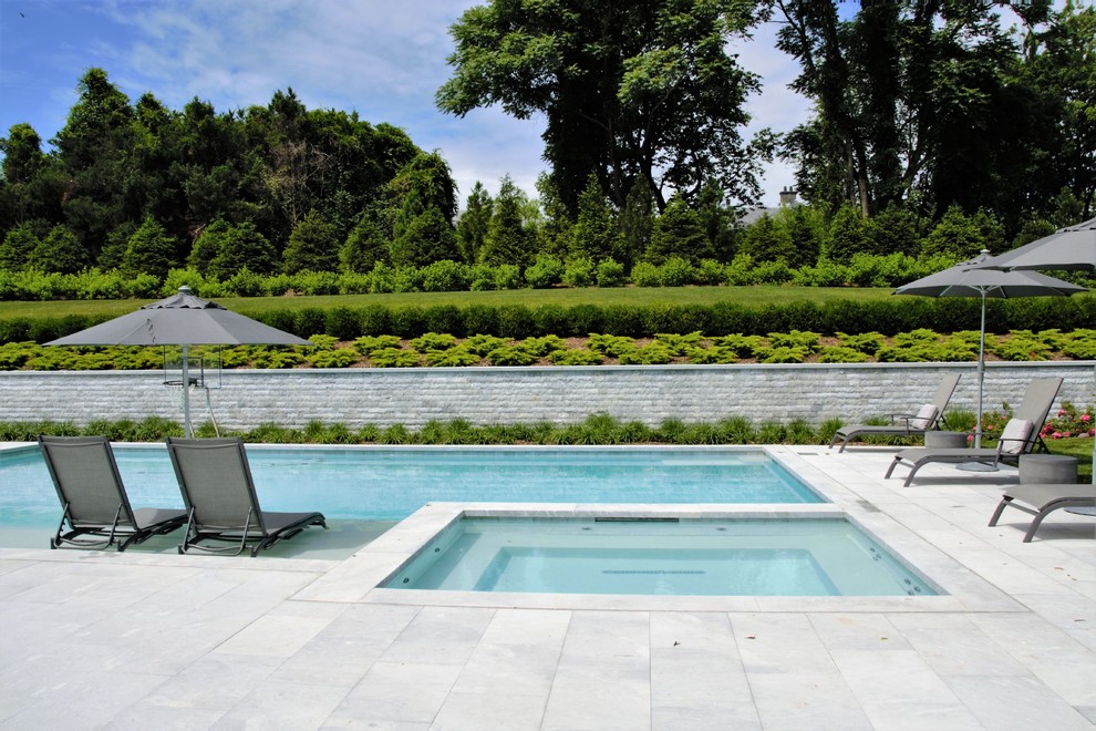 Ispirazione per una grande piscina monocorsia moderna rettangolare dietro casa con una vasca idromassaggio e pavimentazioni in pietra naturale