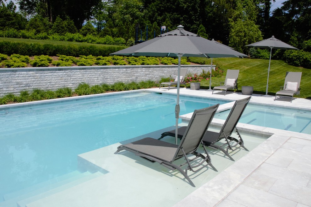 Стильный дизайн: большой спортивный, прямоугольный бассейн на заднем дворе в стиле модернизм с джакузи и покрытием из каменной брусчатки - последний тренд