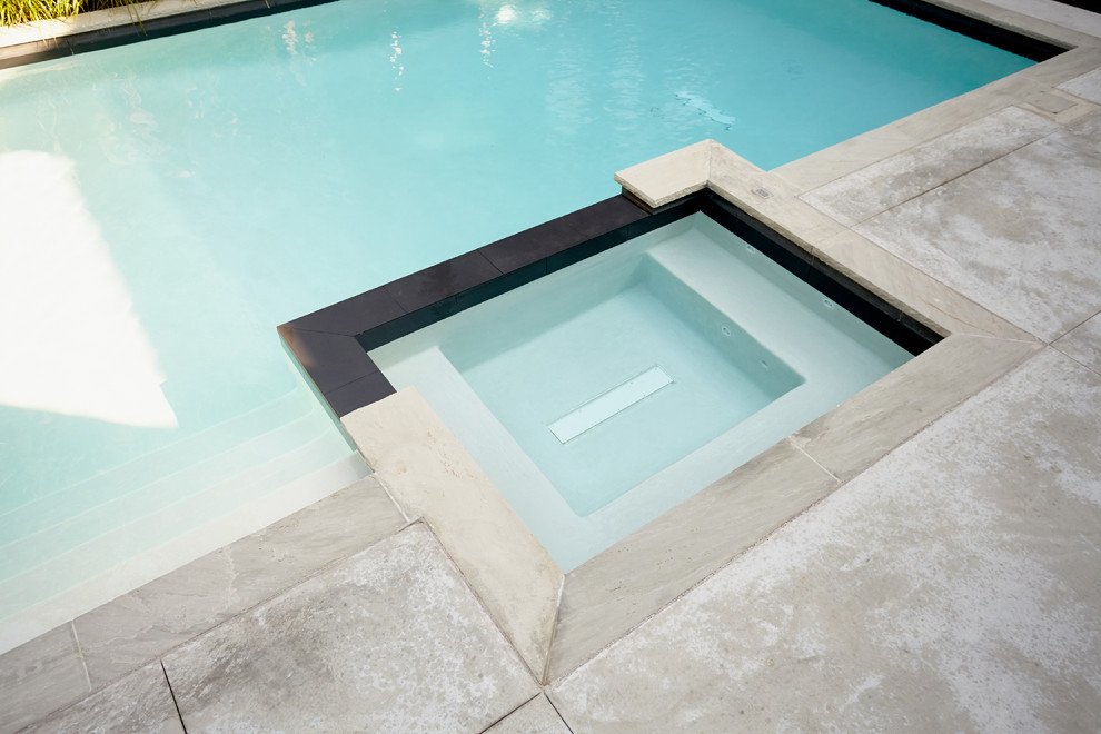 Ispirazione per una grande piscina minimalista personalizzata dietro casa con una vasca idromassaggio e lastre di cemento