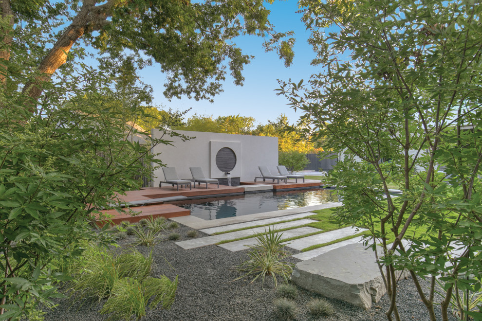 Moderner Schwimmteich hinter dem Haus in rechteckiger Form mit Wasserspiel und Dielen in Dallas