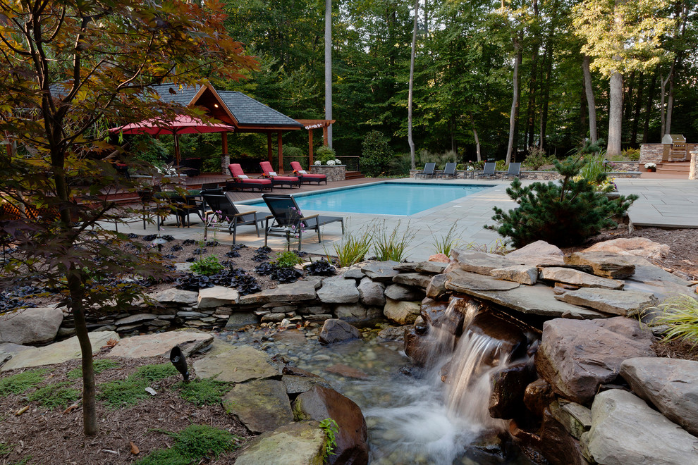 Inspiration for a large tropical backyard rectangular and stone lap pool fountain remodel in DC Metro