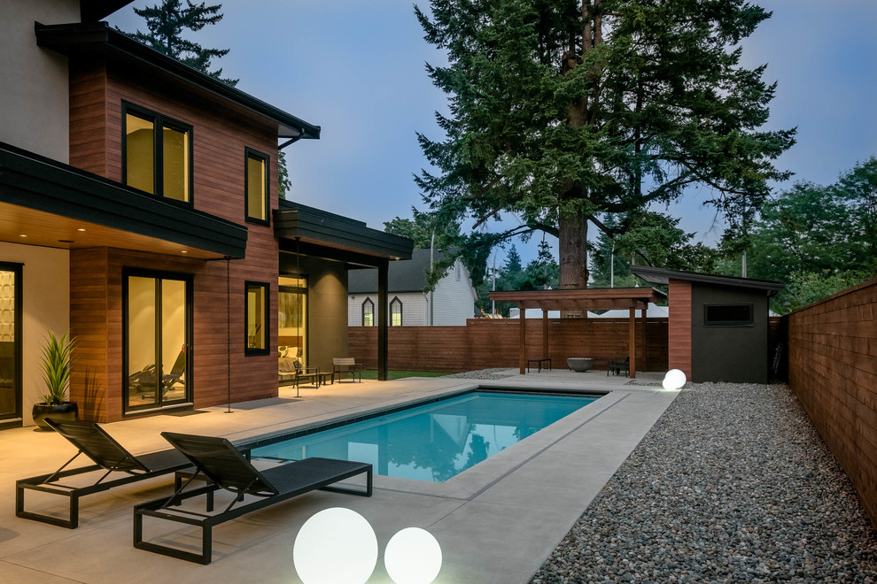 Diseño de piscina retro de tamaño medio rectangular en patio trasero con losas de hormigón