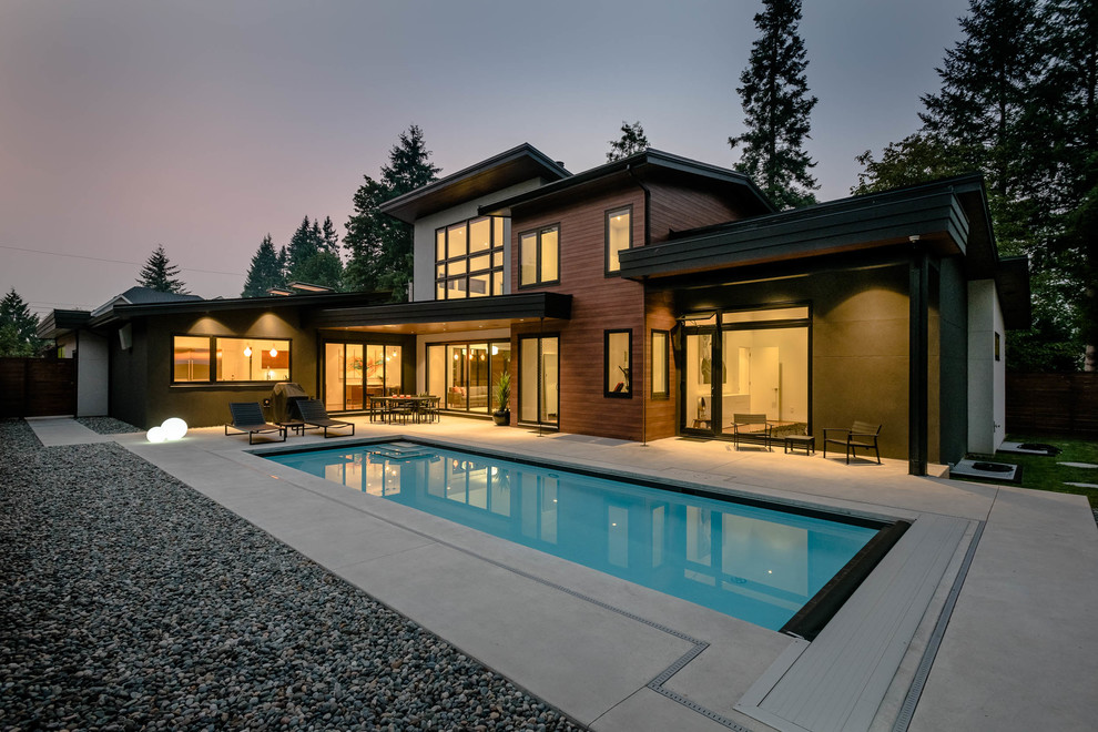Foto di una piscina minimalista rettangolare di medie dimensioni e dietro casa con lastre di cemento