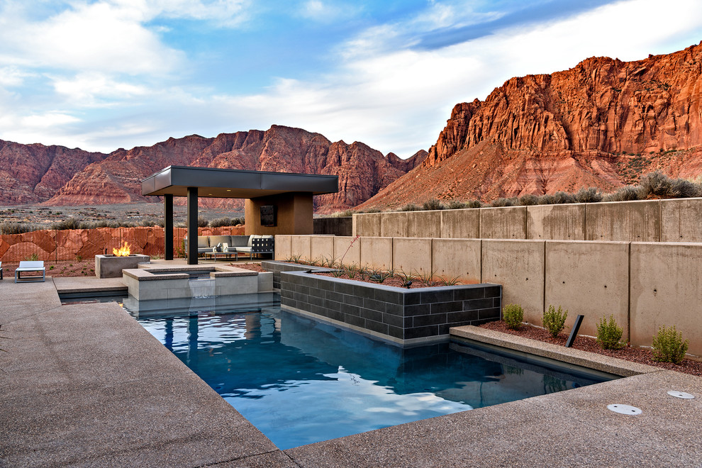 На фото: бассейн среднего размера, произвольной формы на заднем дворе в современном стиле с джакузи и покрытием из бетонных плит с