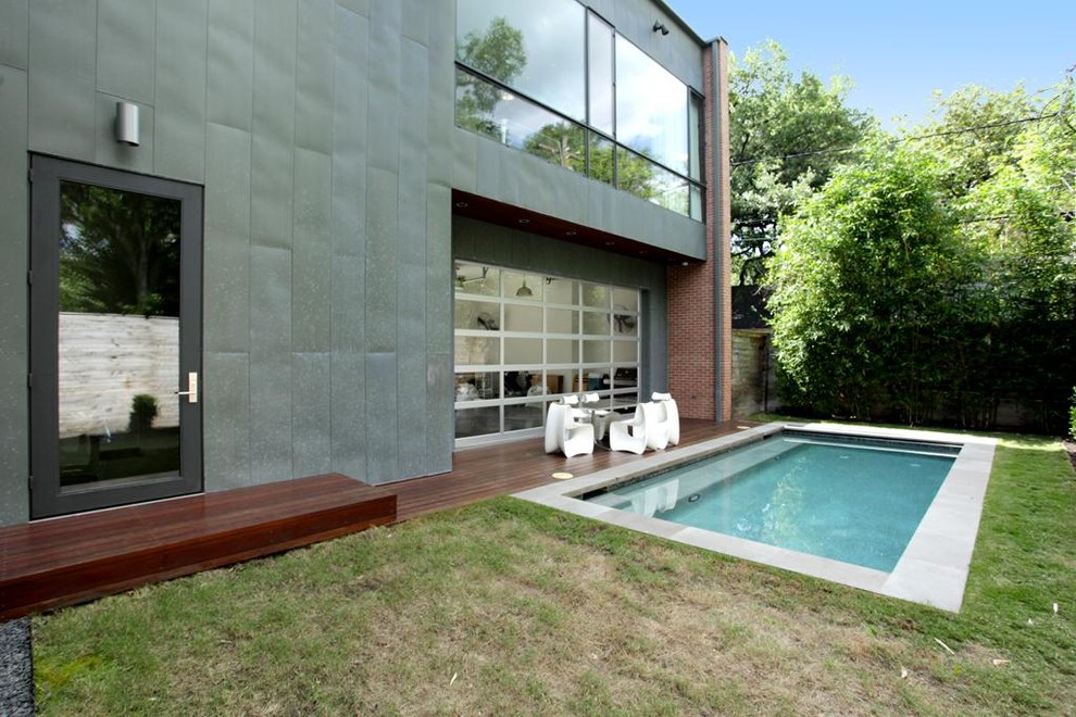This is an example of a small modern back rectangular natural swimming pool in Houston with concrete slabs.