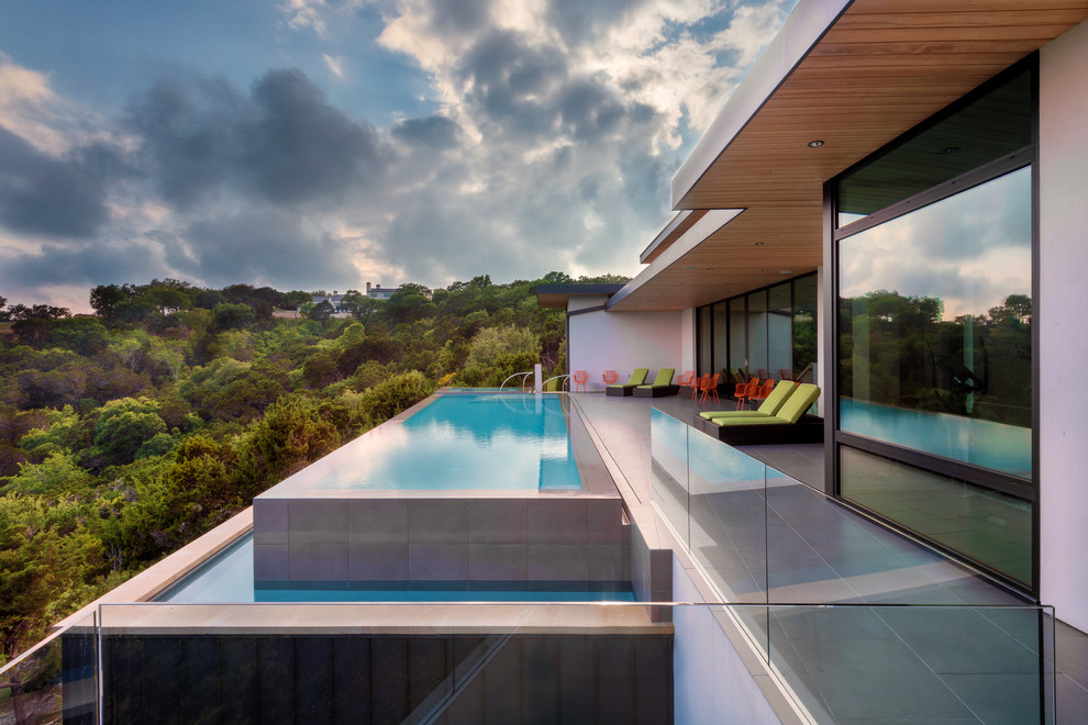 Großer Moderner Infinity-Pool hinter dem Haus in rechteckiger Form mit Betonboden in Austin