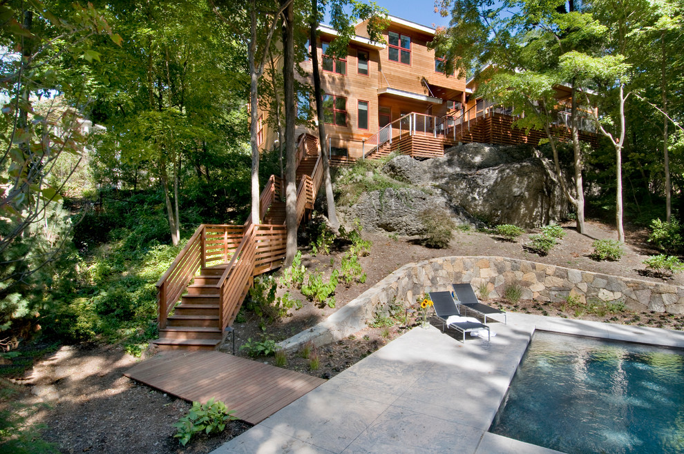 Diseño de piscina alargada minimalista grande rectangular en patio trasero con losas de hormigón
