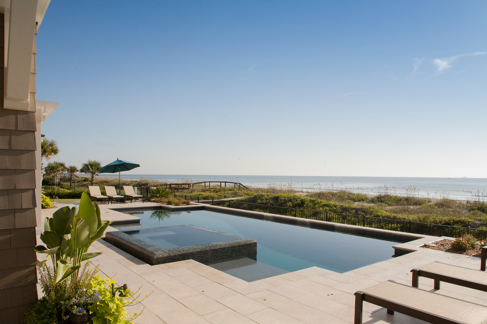 Foto di una grande piscina monocorsia costiera personalizzata dietro casa con una vasca idromassaggio e pavimentazioni in pietra naturale