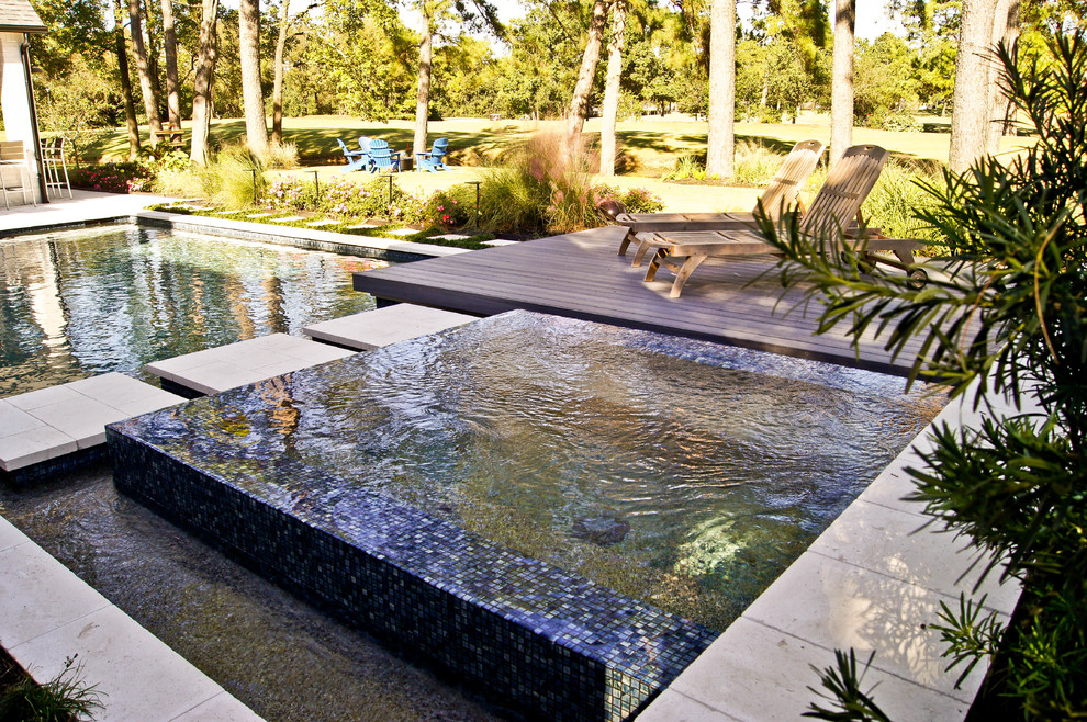 Esempio di una piscina a sfioro infinito minimalista personalizzata di medie dimensioni e dietro casa con una vasca idromassaggio e pedane