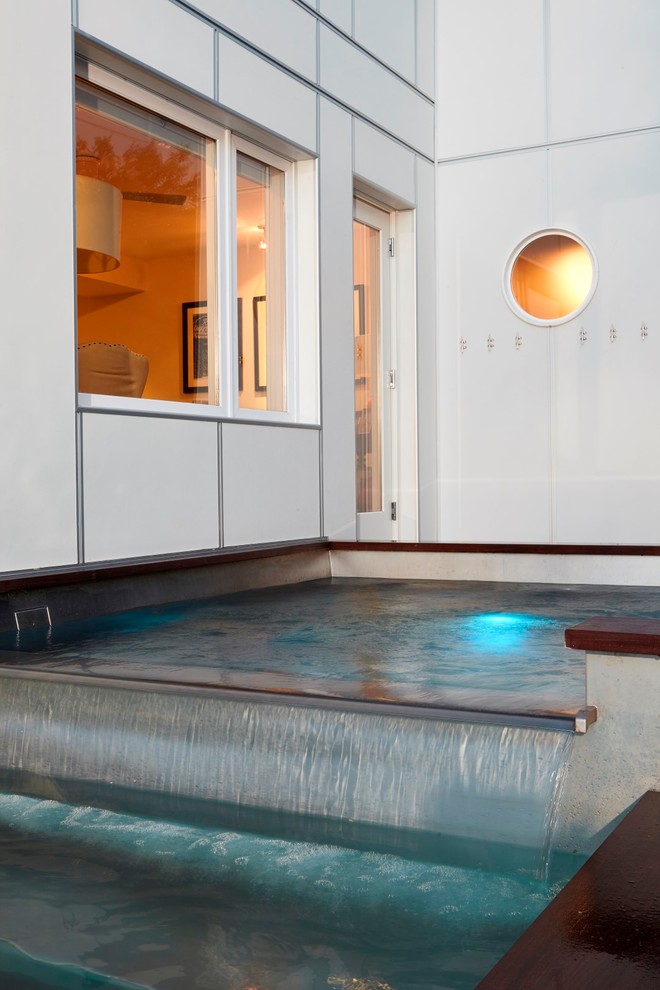 Réalisation d'une piscine hors-sol et latérale minimaliste de taille moyenne et rectangle avec un bain bouillonnant et une terrasse en bois.